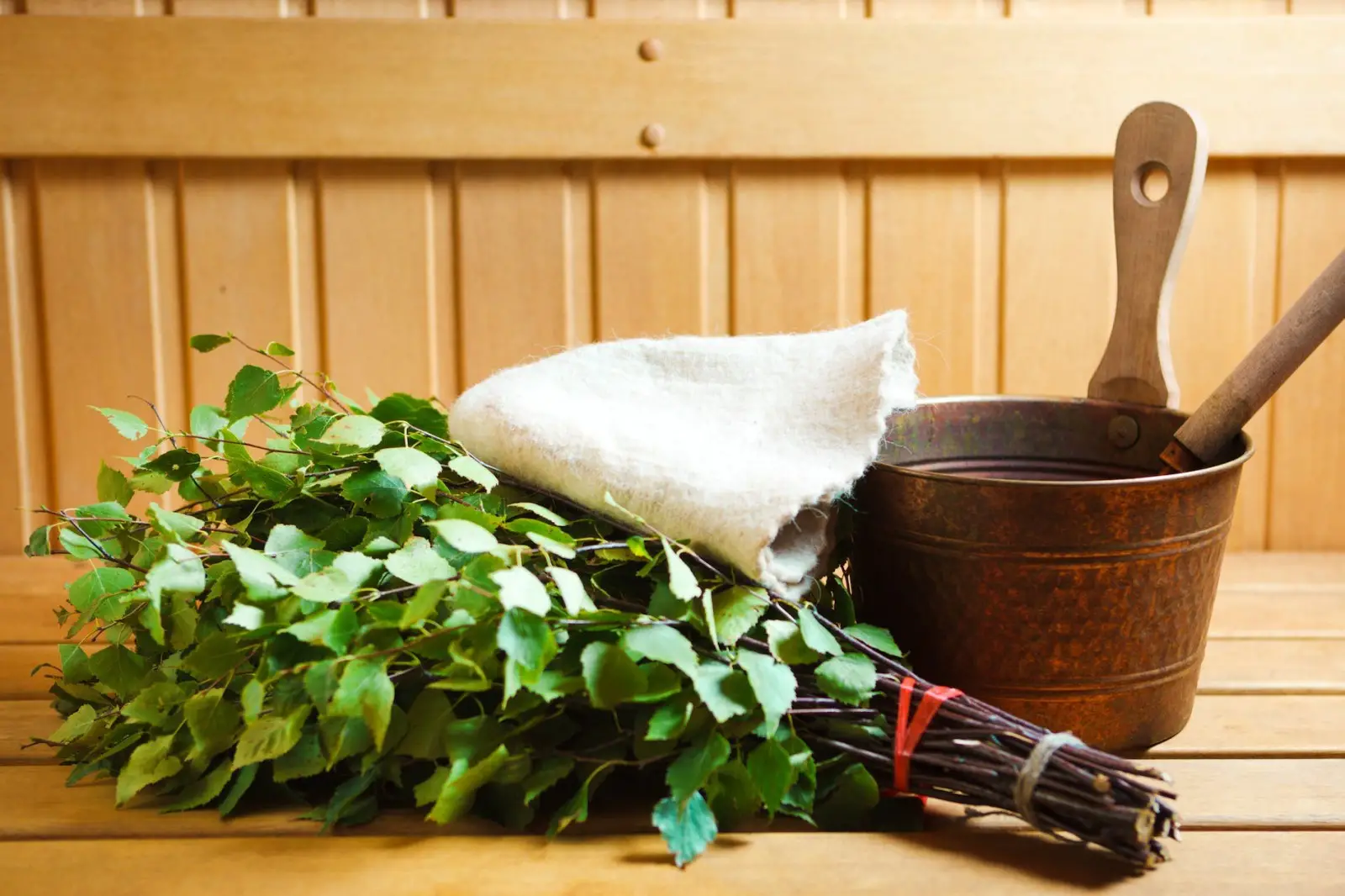 Sauna whisk, towel, and bucket inside a steam room